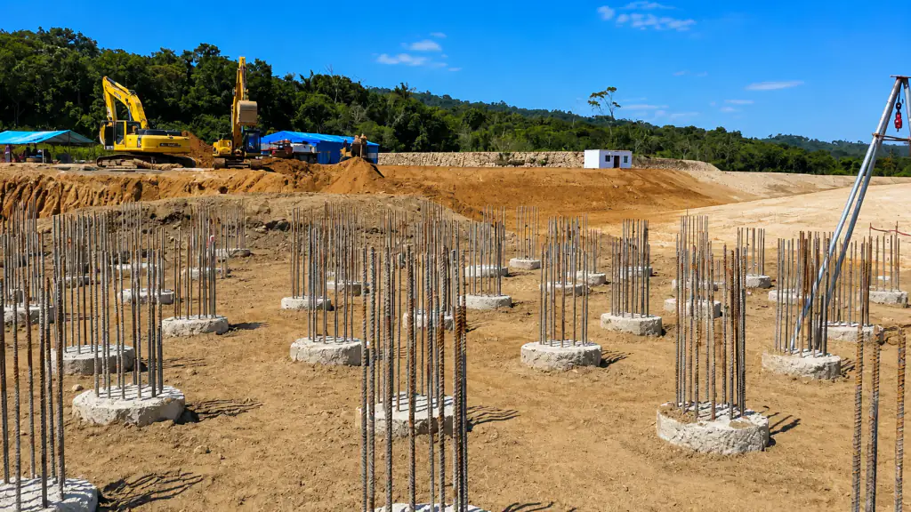 Obra civil con pilotes y cimentaciones en ejecución, maquinaria y trípode de perforación